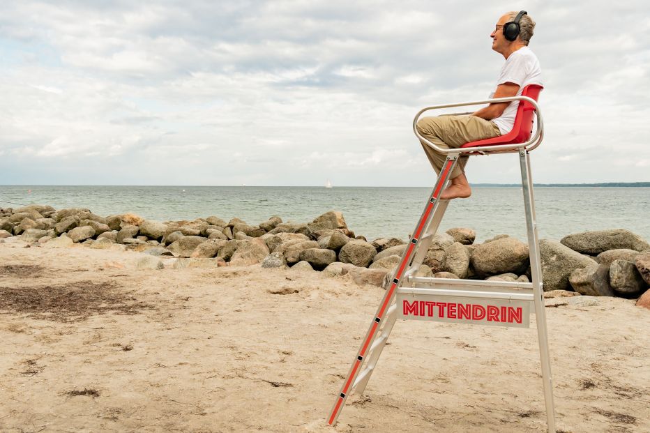 Mann auf Hochstuhl am Strand